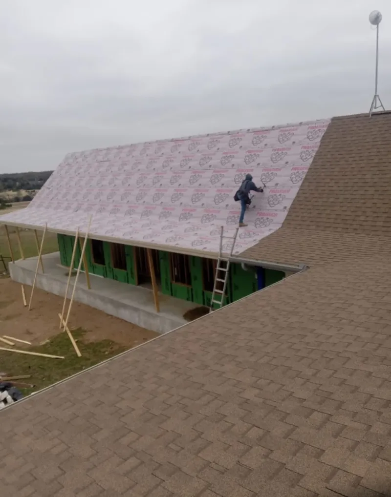 Worker preparing underlayment for a metal roof installation in Sherwood